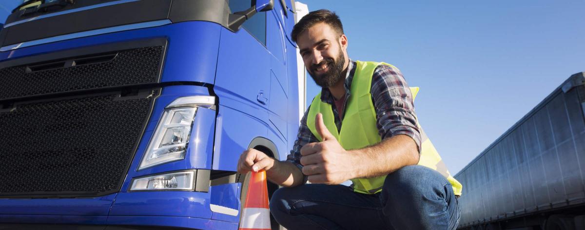 Un routier souriant devant son véhicule poids lourd à Périgny