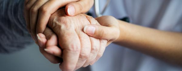 Une infirmière tiens la main d'une retraité.